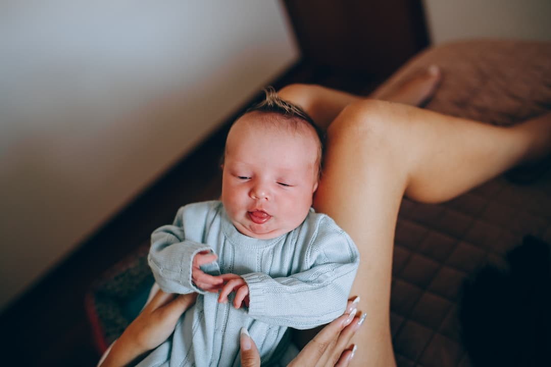 woman carrying baby in blue and white blanket