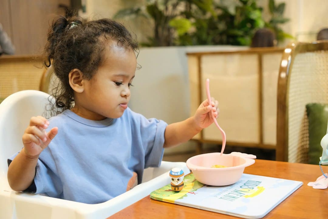 Young child eating with a pink spoon and bowl