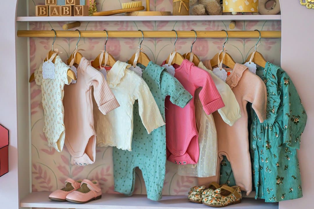 Baby clothes hanging on a rack with shoes below shoes
