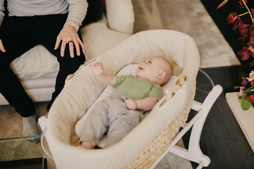 baby in green onesie lying on white and brown crib