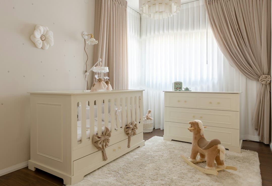 A cream-colored nursery with a crib, a dresser, and a plush rocking horse on a rug