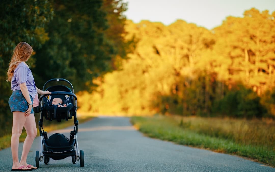 Woman pushing a baby stroller on a country road