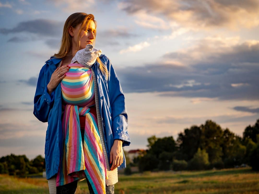 woman in blue pink and yellow dress standing on green grass field during daytime