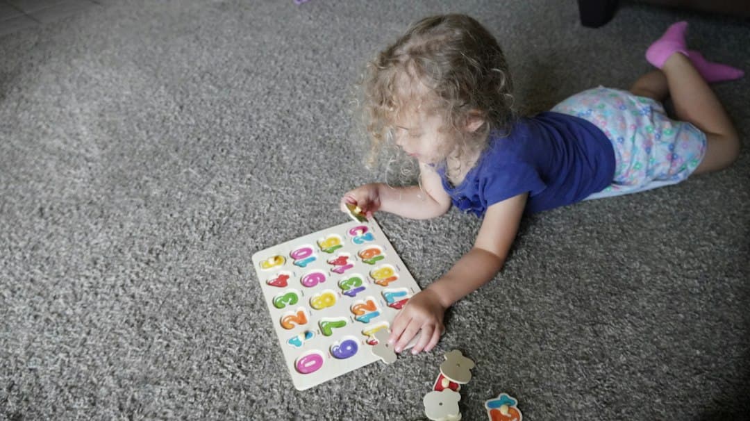 Toddler playing with alphabet puzzle on carpet